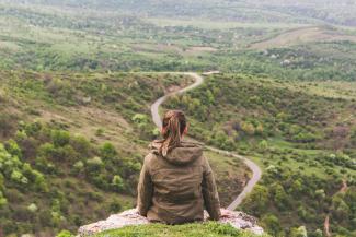 woman sitting on grey cliff by Vlad Bagacian courtesy of Unsplash.